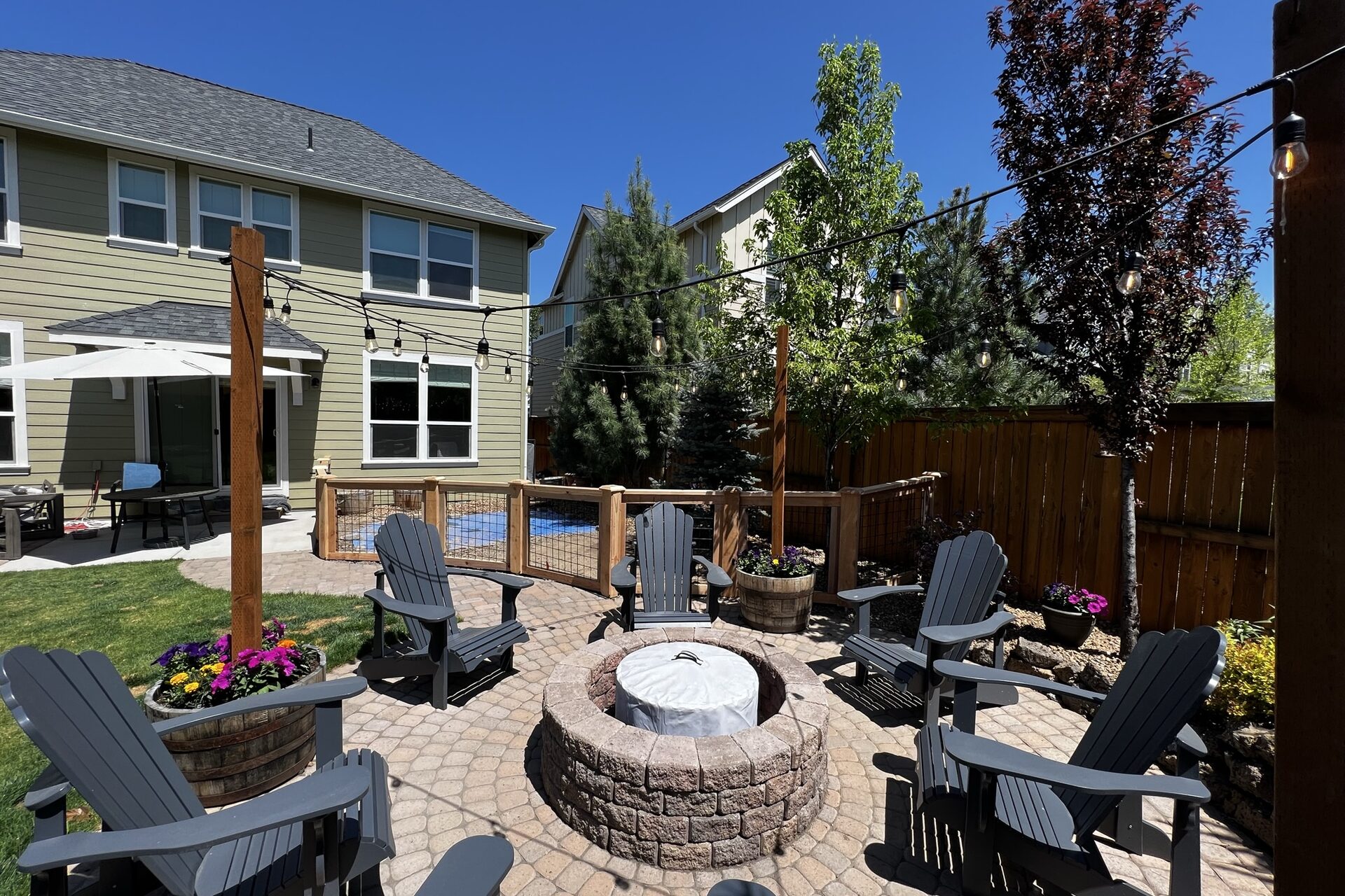 Lush green Central Oregon backyard with cedar fence, patio and fire pit built by High Pine Construction